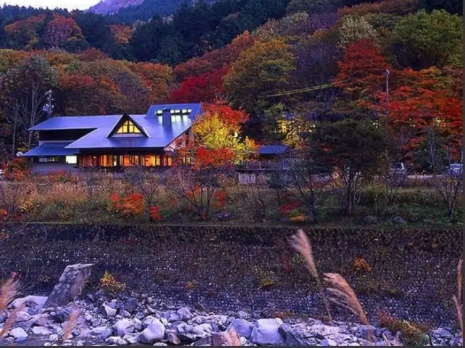 Onjuku Kajika with this scene, where its building glows among red and gold trees beside the valley road.