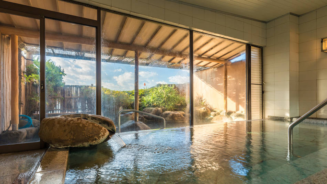 An indoor bath with glass doors opening toward a garden.