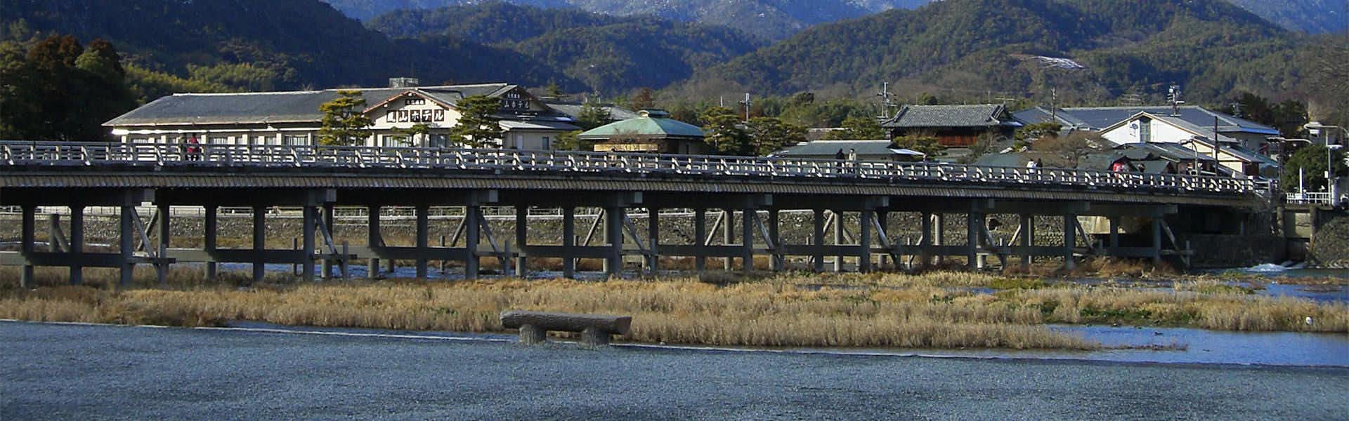 Arashiyama Onsen Saishiki no Yado Hanaikada with the Togetsukyo Bridge stretching across the calm river.