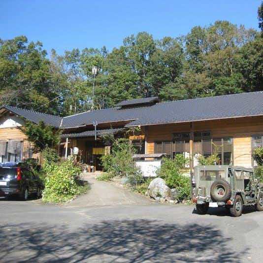 Yunosawa Kosen rustic wooden lodging exterior beside a driveway and forest