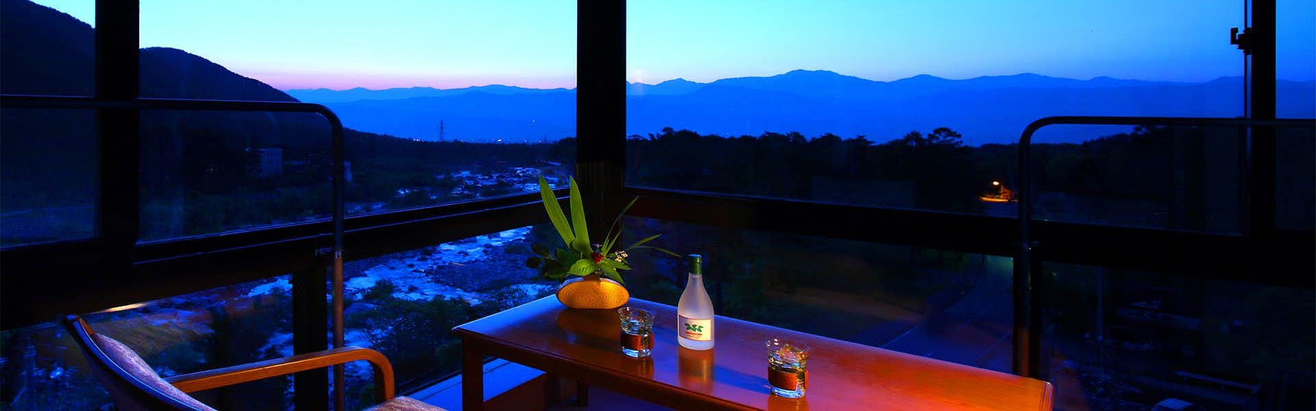 Futari Shizuka with this scene, where a private room lounge frames layered mountain silhouettes at twilight.