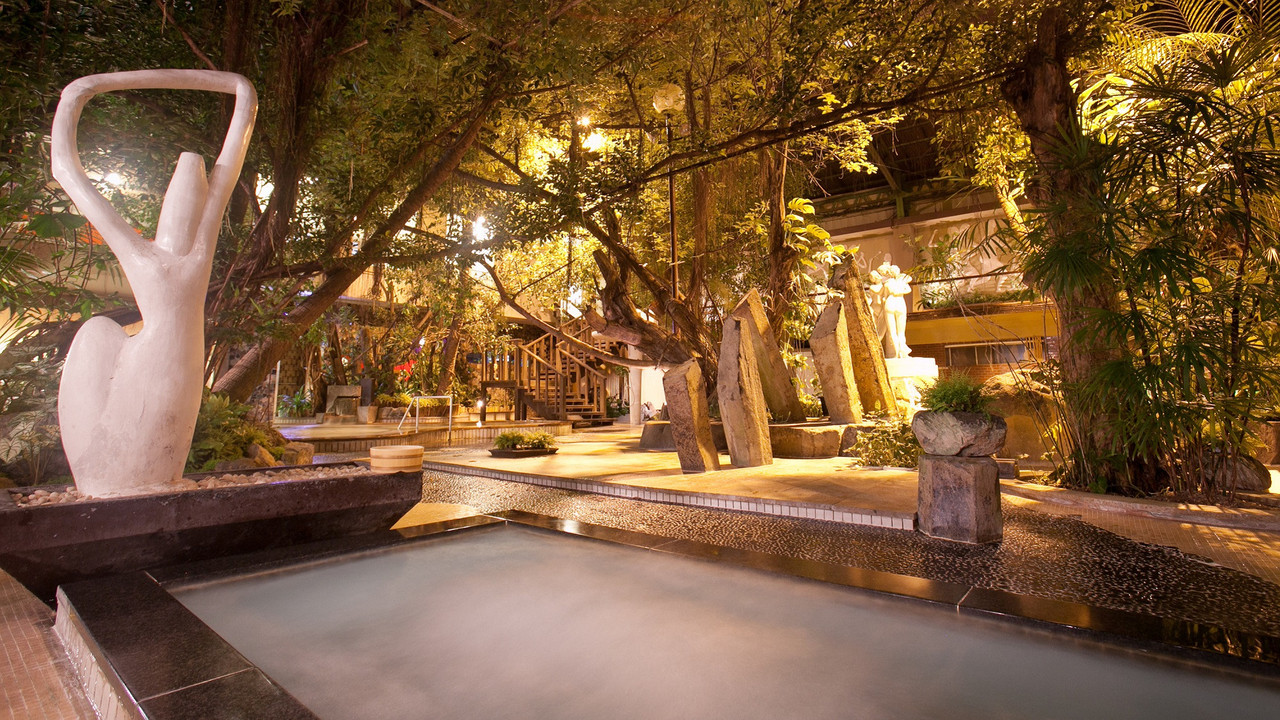 A landscaped outdoor bath beneath trees.