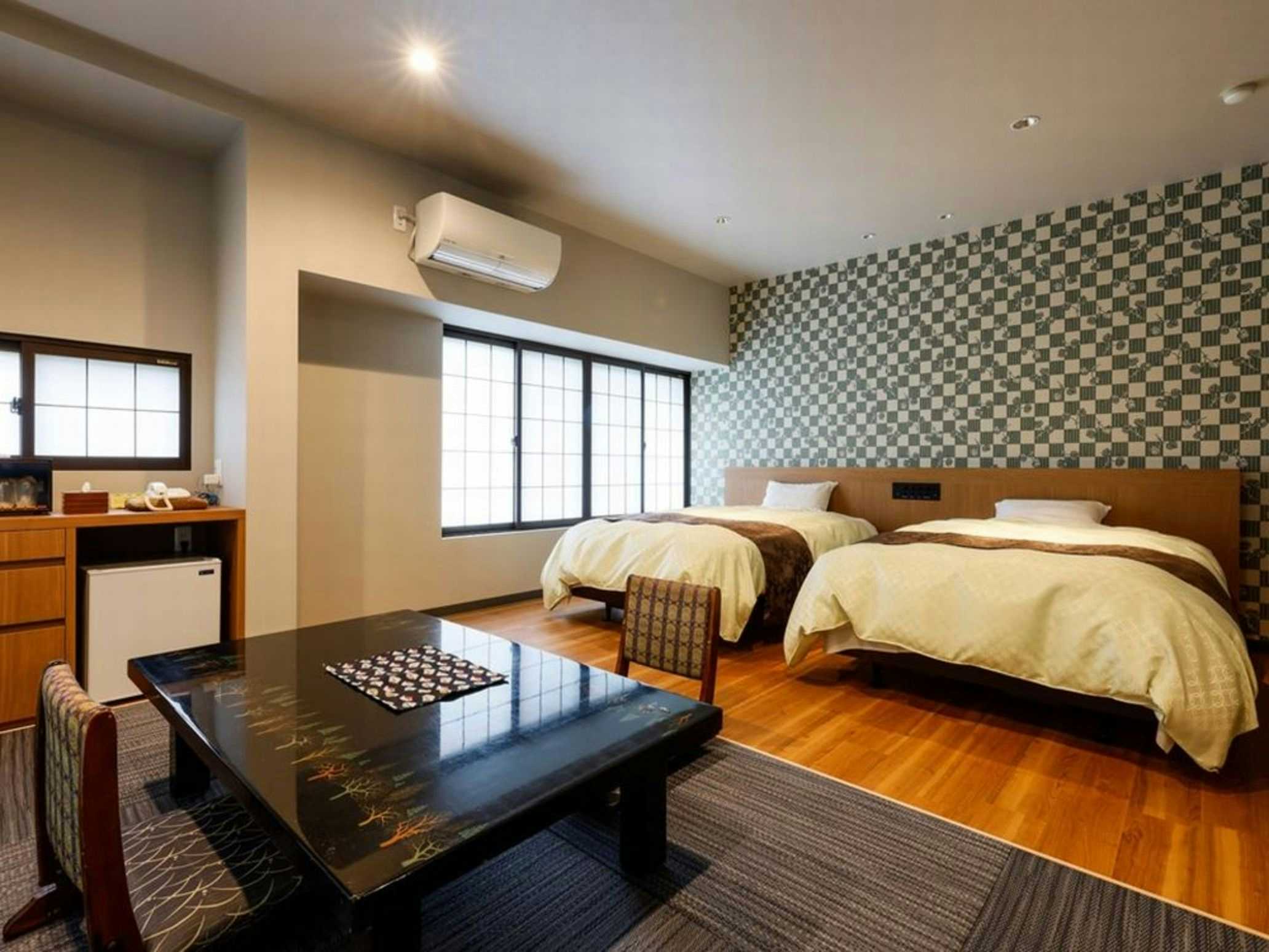 Kinosaki Onsen Hanamandara Interior space with tatami-style flooring, grid-pattern sliding doors, natural light, low wooden furniture, and warm wood tones.