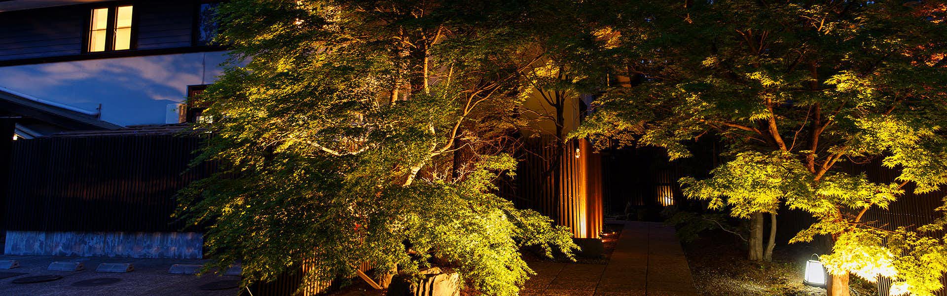 Nasu no Yado Enishi with a tree-filled garden, pathway lights, and a dark blue sky