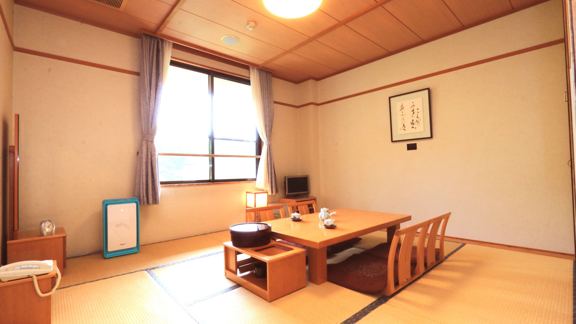 A tatami guest room with a low table and chairs beside a window.