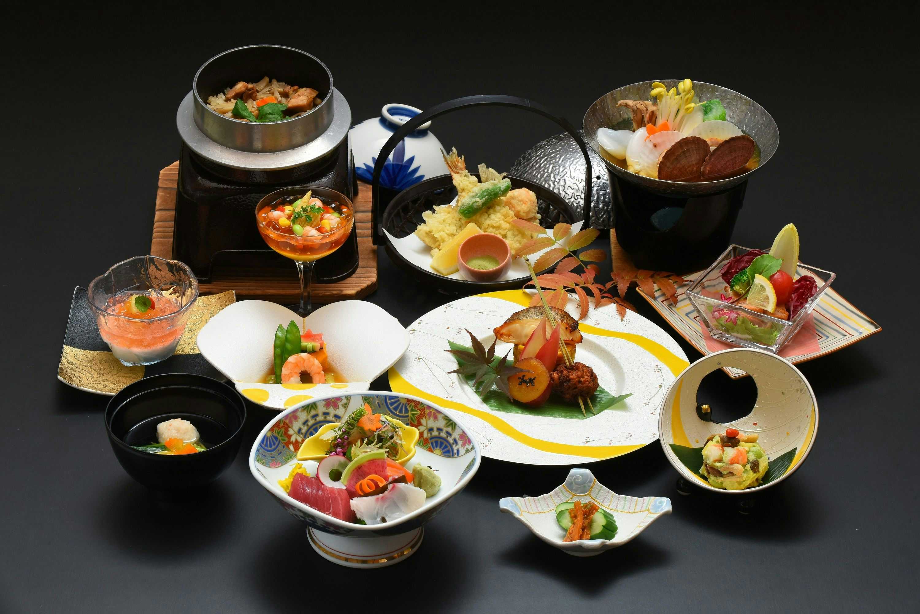 Fujiya Hotel Multi-course meal with various prepared dishes arranged on black plates and bowls against dark surface.