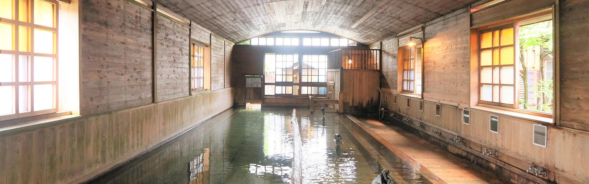 Senninburo Kanaya Ryokan with a long timber-lined communal bath beneath an arched ceiling.