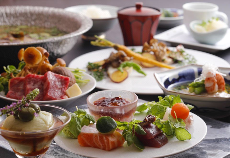 Table spread with assorted Japanese dishes, including beef, sashimi, vegetables, and small side plates.