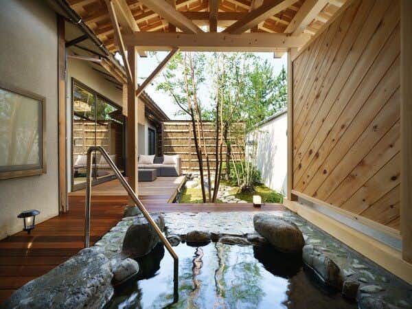 Tsukioka Onsen Yuasobi Yado Akebono rock-lined outdoor bath beneath a wooden roof beside a small courtyard