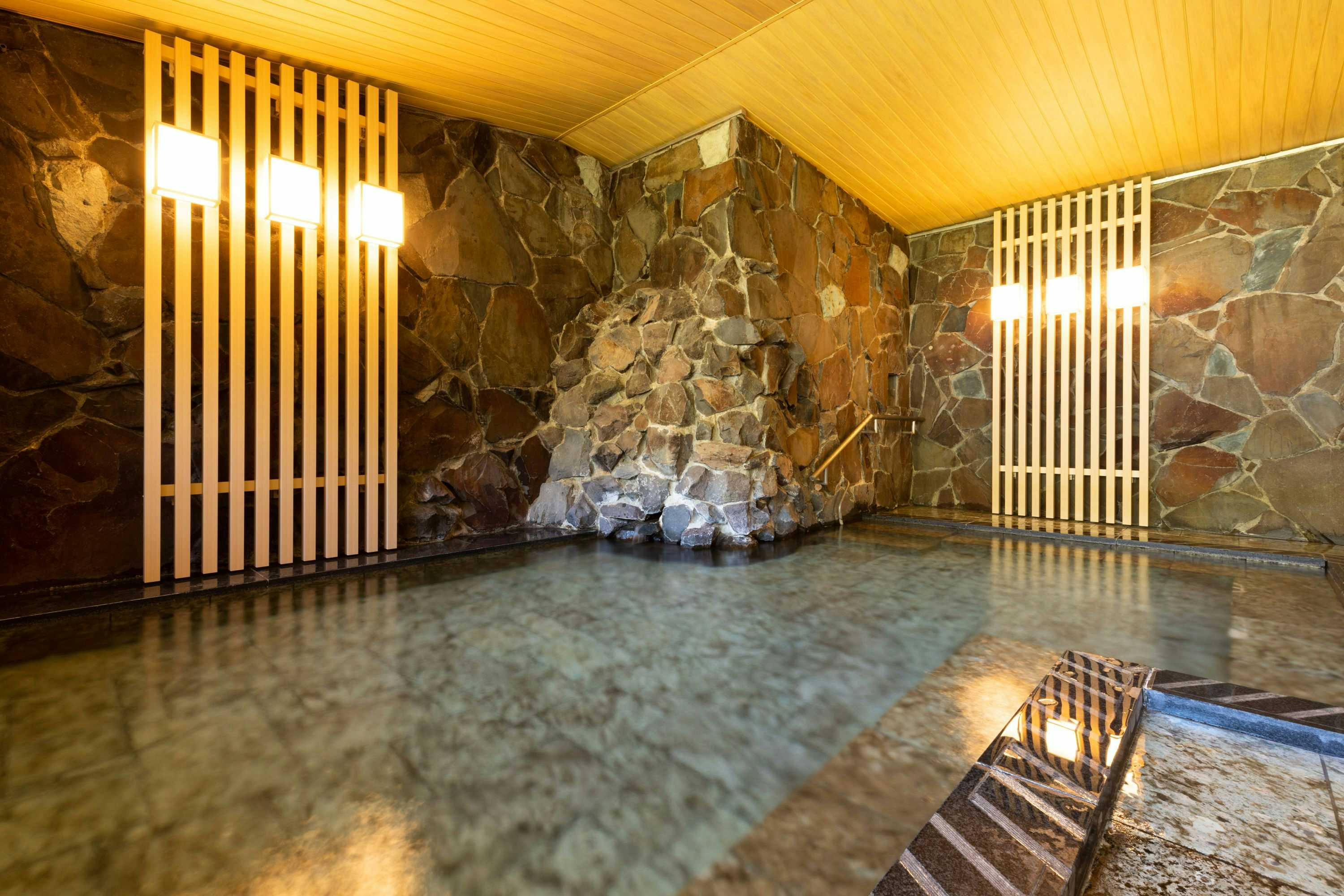 Forest Resort Yugawara Mizunokaori with a stone-lined indoor bath beneath pale timber slats.