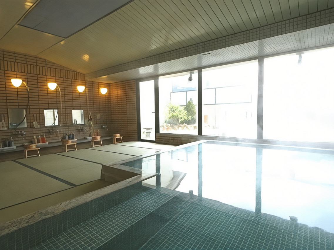 A large indoor bath beside bright windows and a row of shower stations.