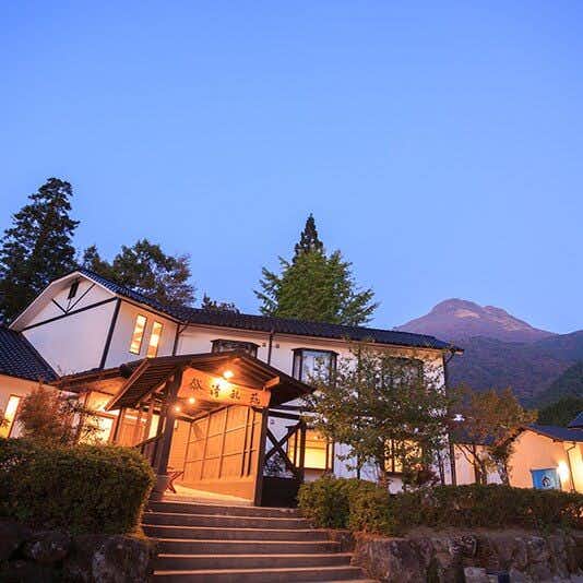 Yufuin Ryokan Seikouen illuminated lodging exterior beneath a mountain at dusk
