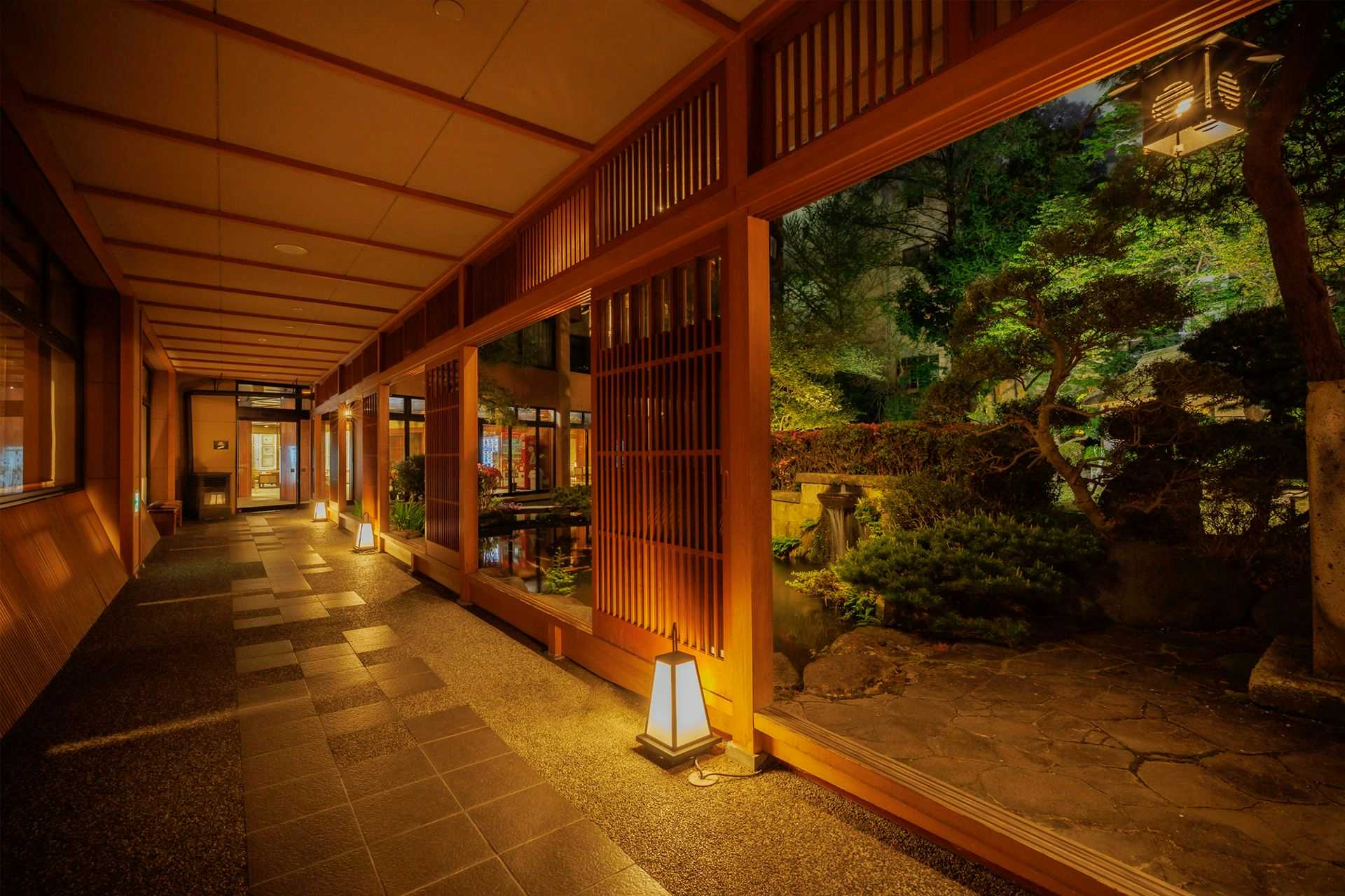 Takinoyu Hotel with a lantern-lit timber corridor overlooking a dark garden.
