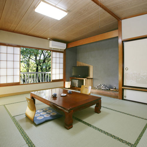 A Japanese guest room with a low table beside a window overlooking trees.