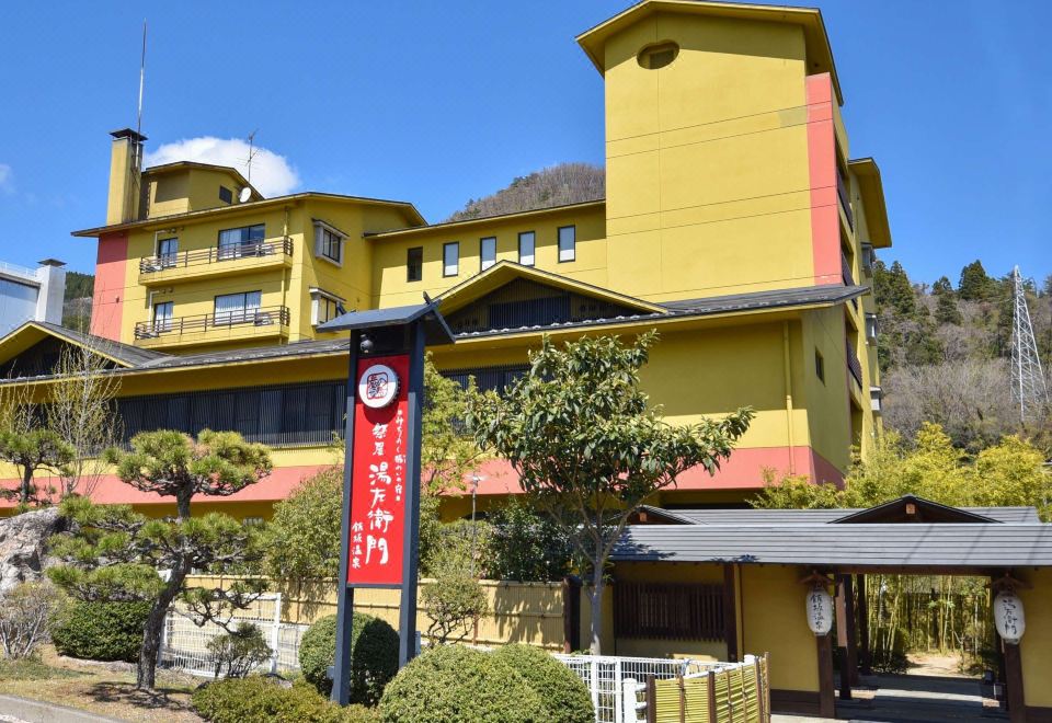 A colorful building sits against a wooded hillside.