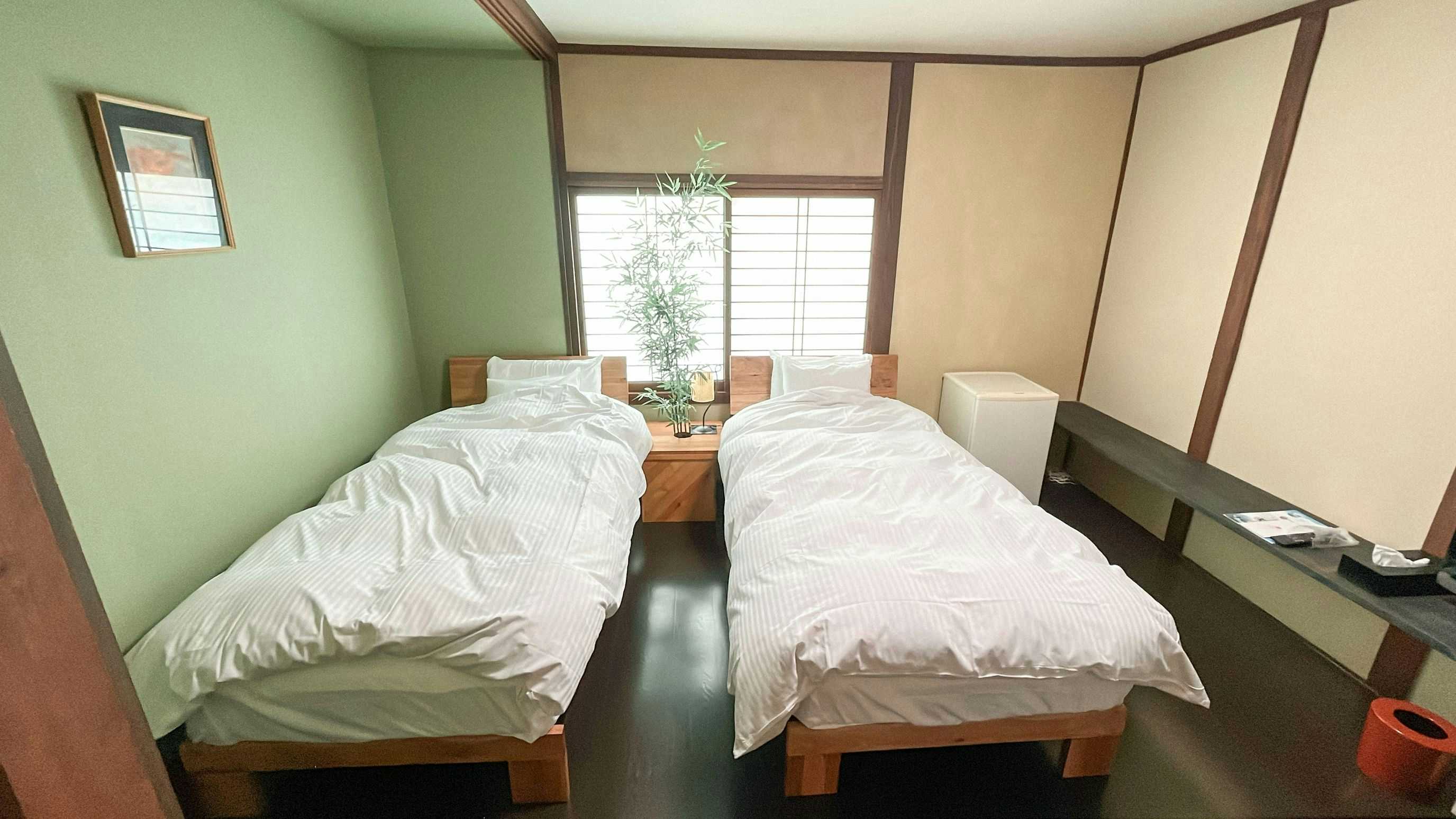 Chidori Ryokan with a compact twin bedroom with pale bedding and green walls.