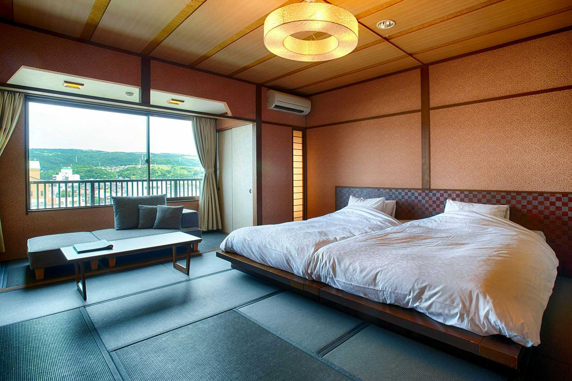 Kouyurou Ikawa with a tatami bedroom with low bed and wide valley windows.