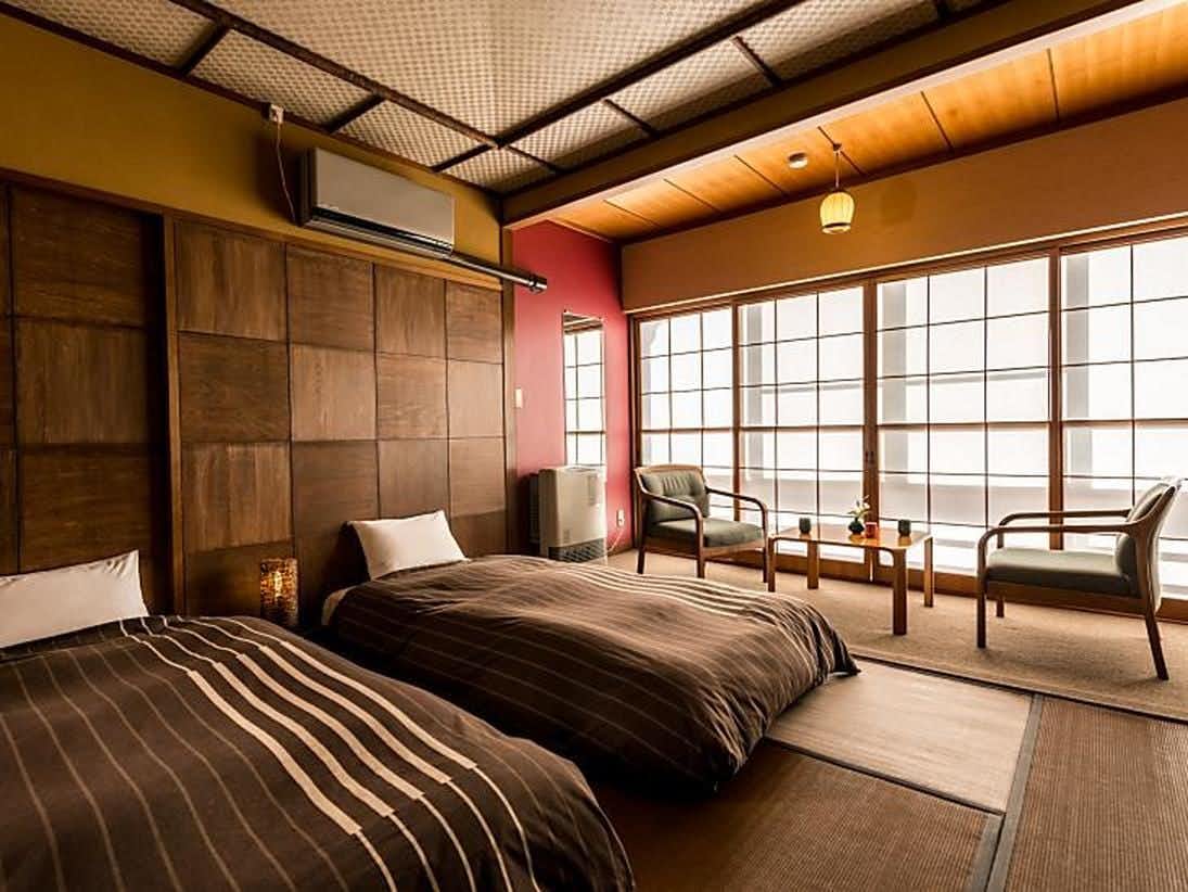 Yumori Takumi-an Yamakawa with a contemporary twin room with striped brown bedding.