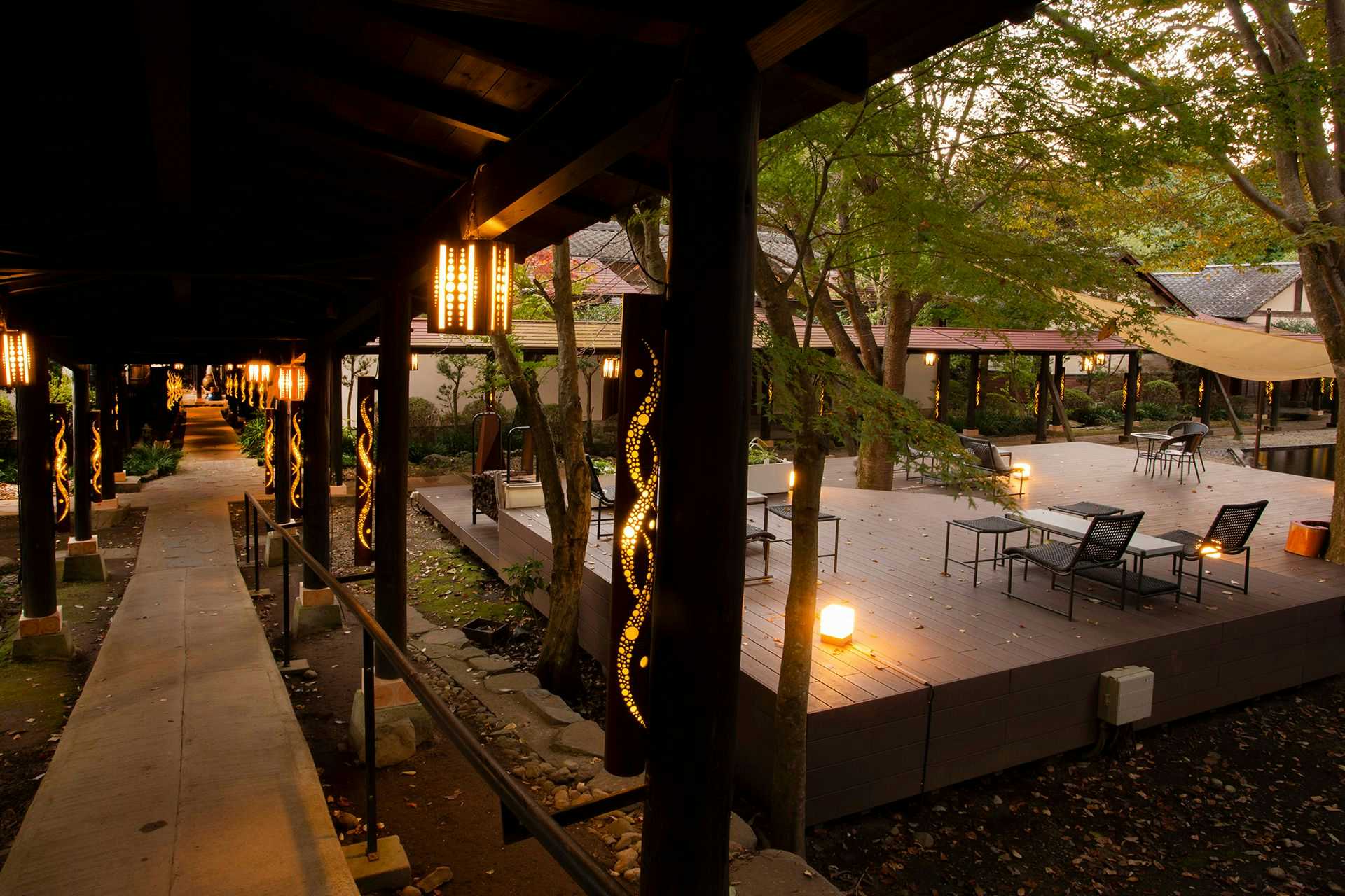 Minami Aso Tawarayama Onsen Ryokan Chikurakutei Covered wooden corridor with strung lanterns, timber posts, and paved walkway extending into distance