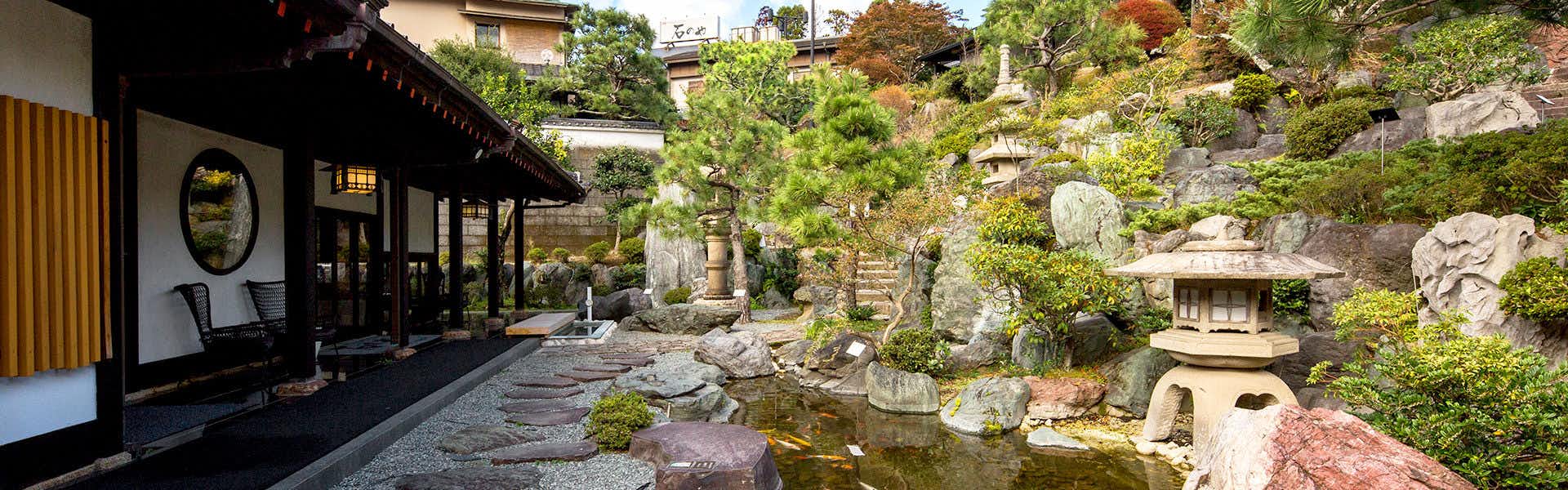 Ishinoya Izunagaoka with a landscaped courtyard with stone lanterns and clear water.