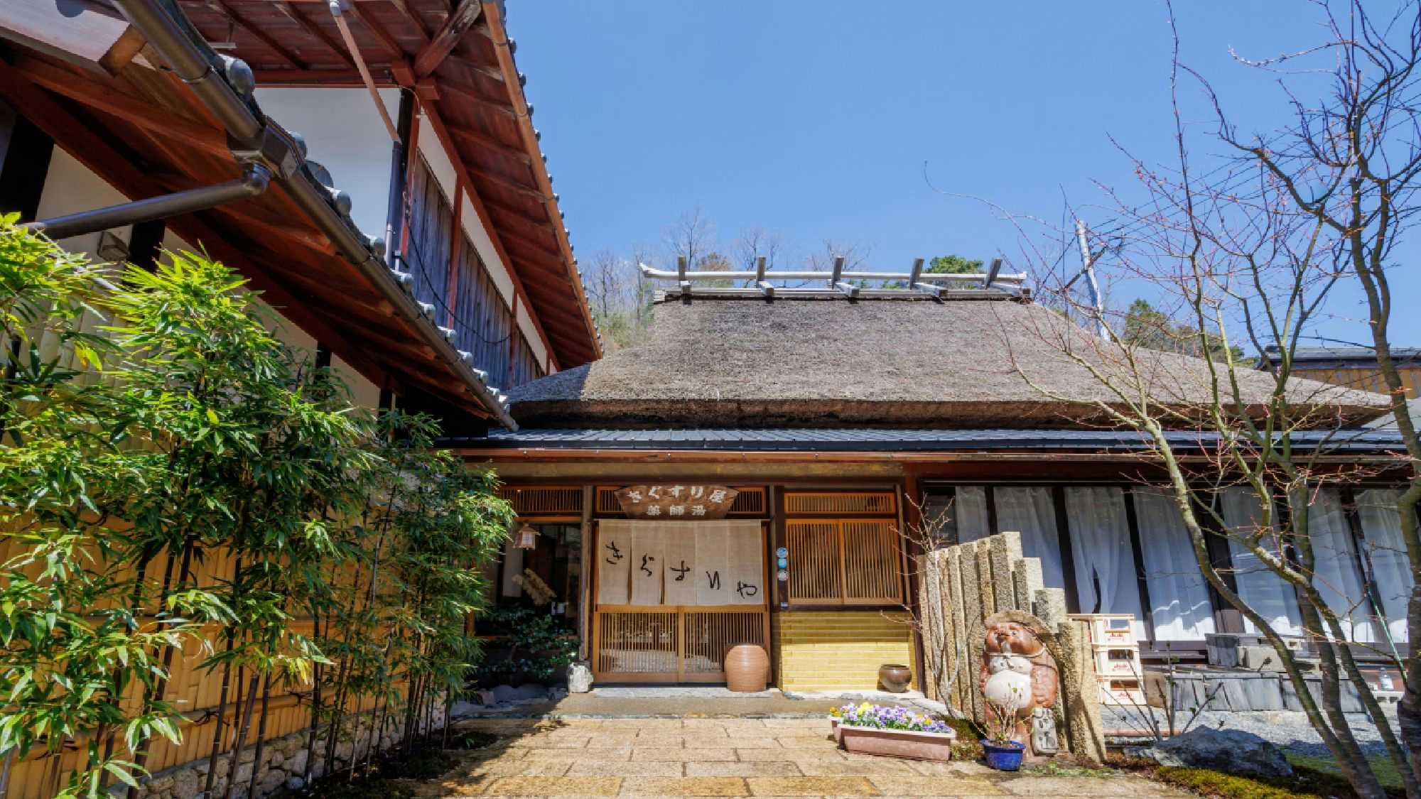 Cuisine Ryokan Kigusuriya with a thatched timber building framed by garden greenery.