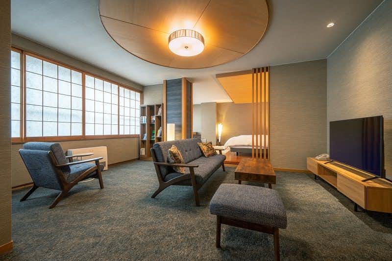 Matsudaya Ryokan with a contemporary sitting room with broad shoji windows and low seating.