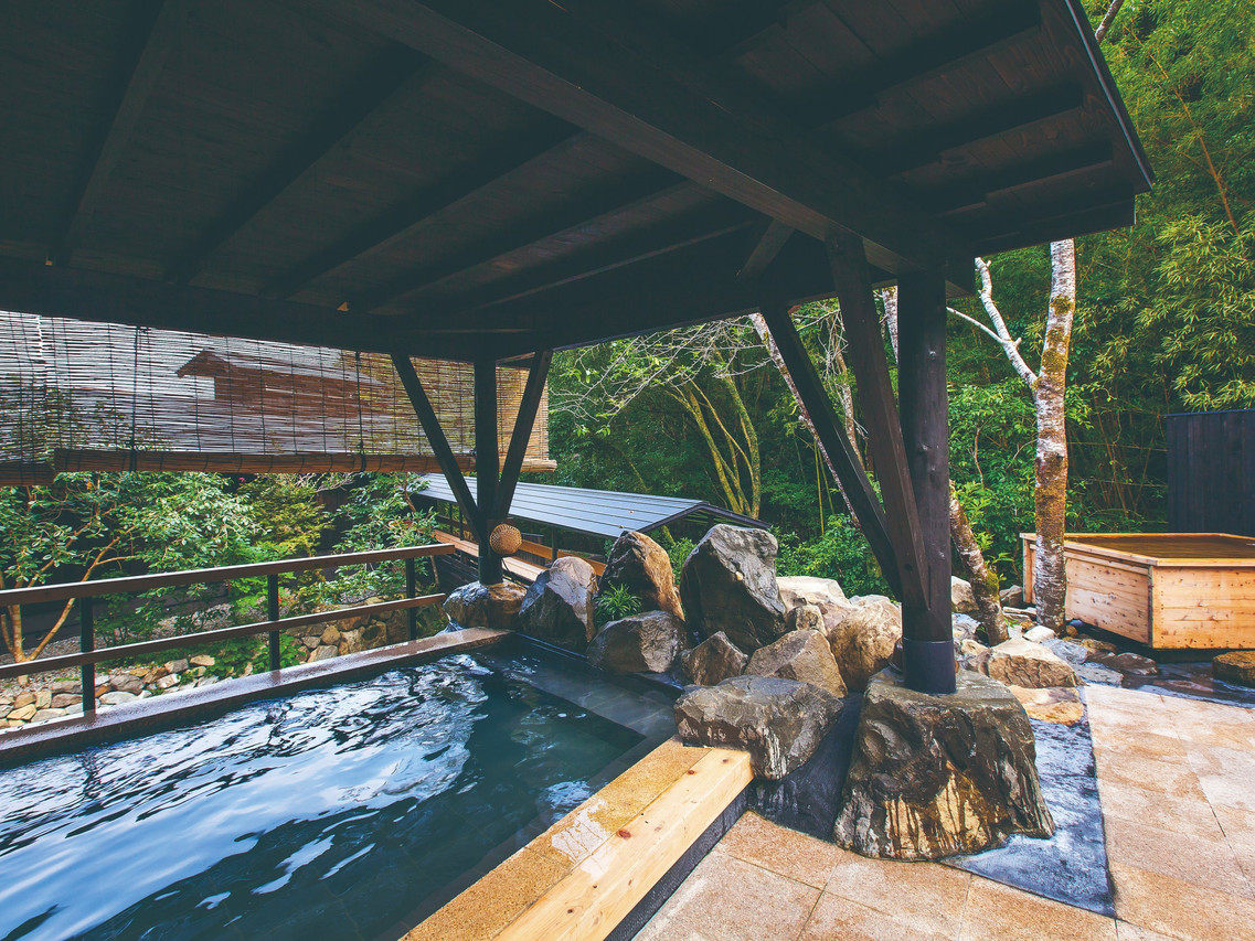 Covered outdoor bath with a rock surround.