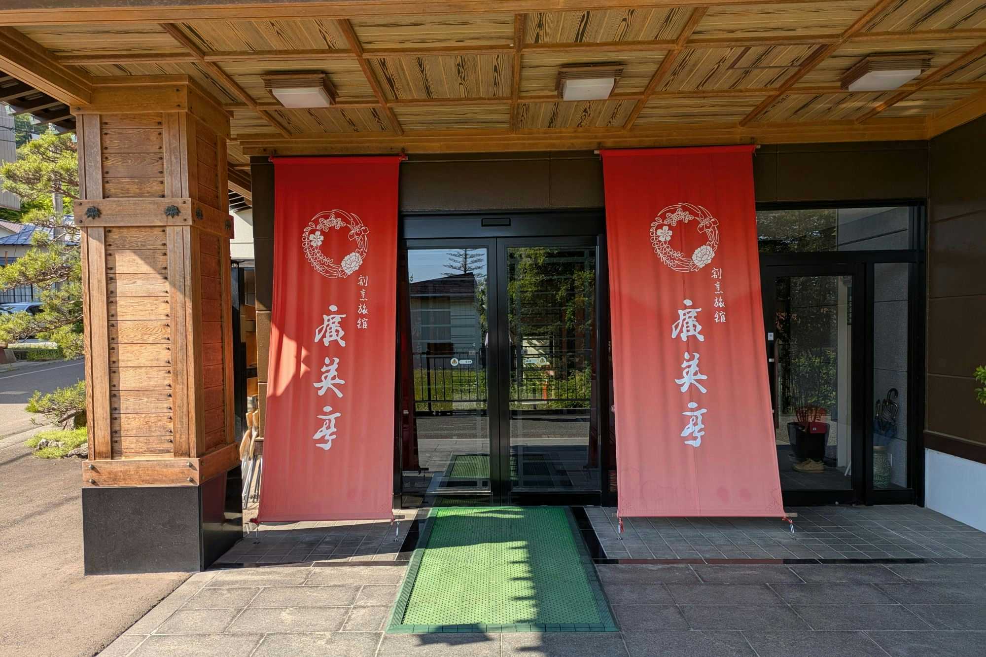 Kappo Ryokan Hiromitei with this scene, where its entrance is marked by red noren panels beneath a carved timber canopy.