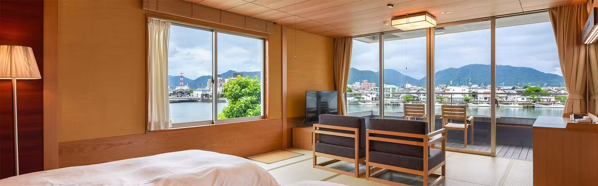 Hagi Hakkei Ganjima Bessou with this scene, where a river-facing guest room pairs a low western bed with window-side seating.