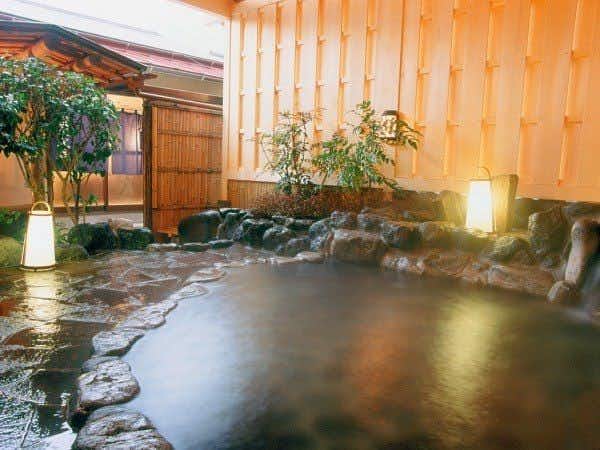 Izu Nagaoka Onsen Koubou no Yu Ikona-so with an outdoor stone bath surrounded by timber and greenery.