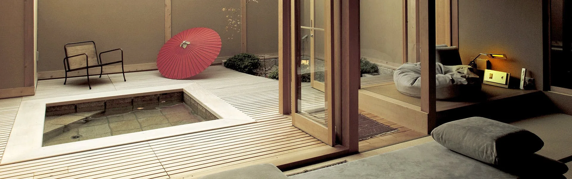 Private rotenburo terrace with cedar deck and red wagasa parasol at Miyahama Onsen