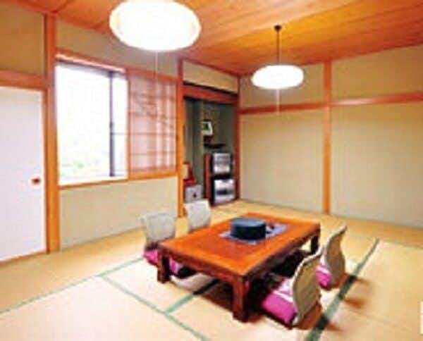 Shinyu Onsen Kurikoma-so with a simple tatami room with low table and red cushions.