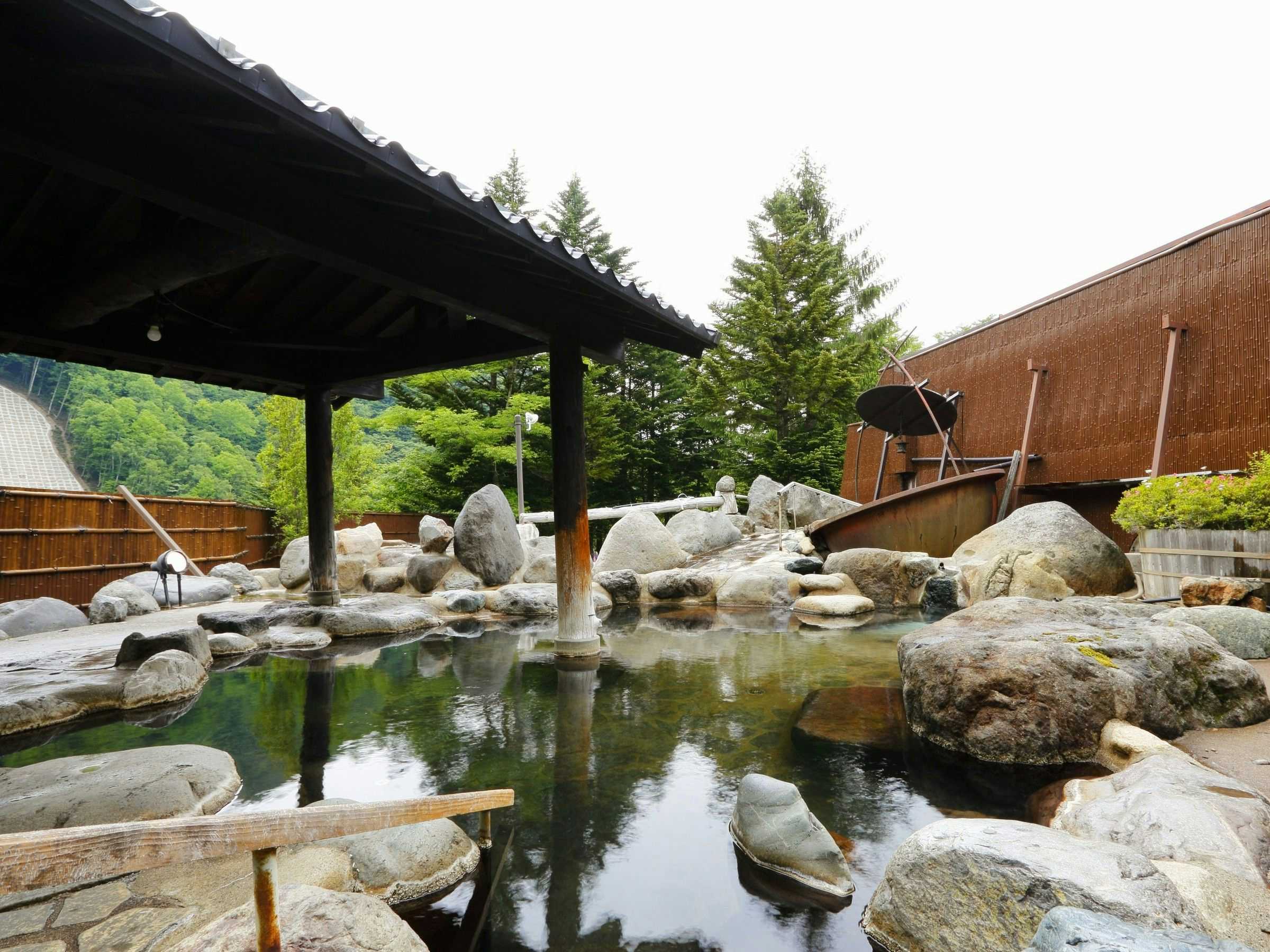 Okada Ryokan Warakutei with a broad open-air rock bath under a timber canopy.