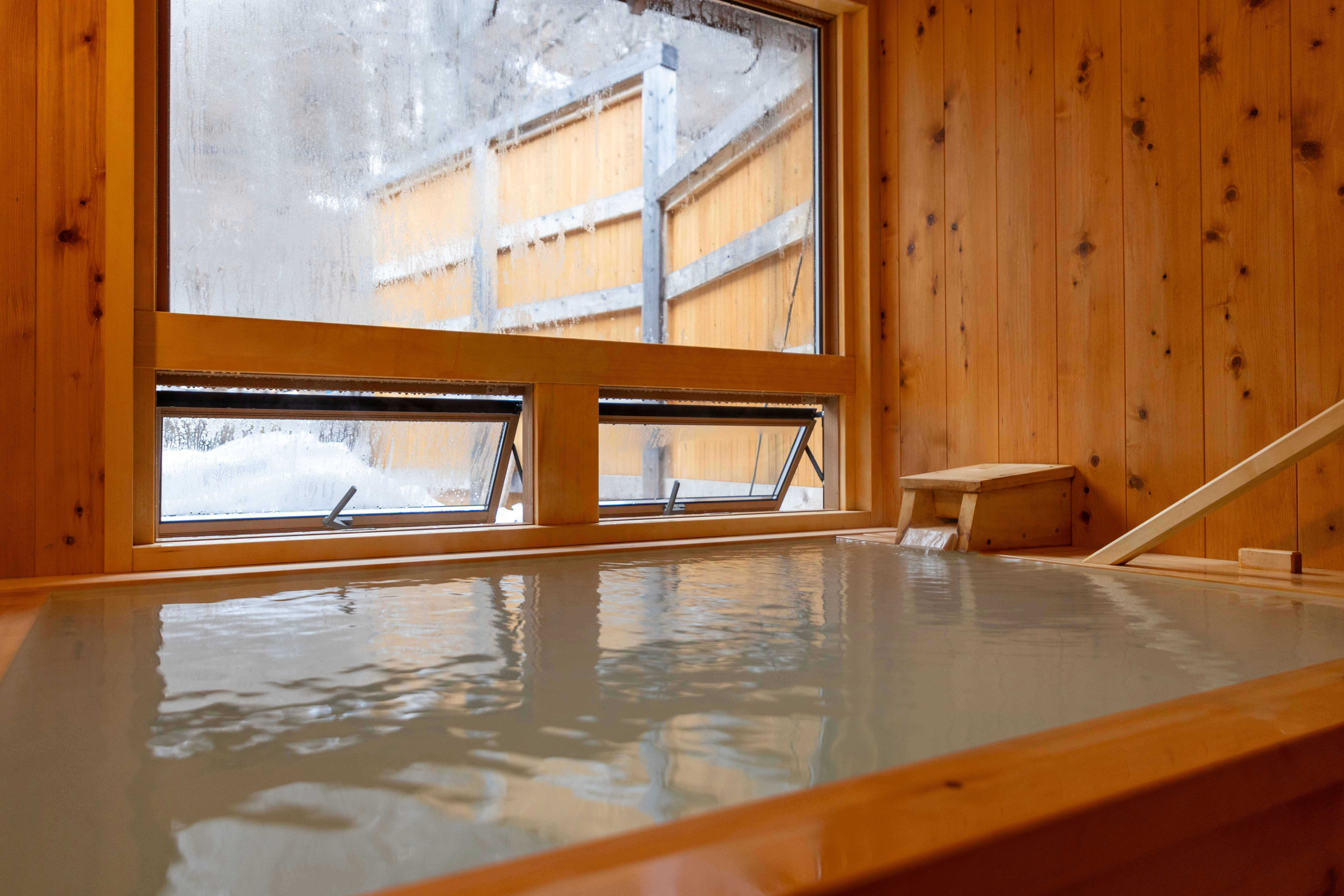 Onsen Ryokan KODAMA with a serene indoor bath beneath high timber walls.