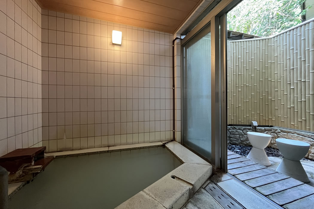 Indoor bath with tiled walls and a bamboo-screened outdoor area.