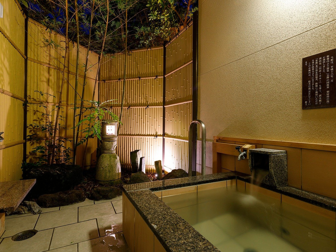 A room with a covered outdoor bath and garden view.