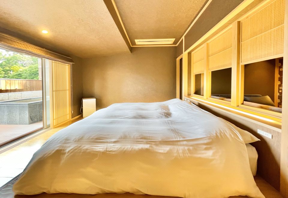 A bedroom with a large bed beside a window.