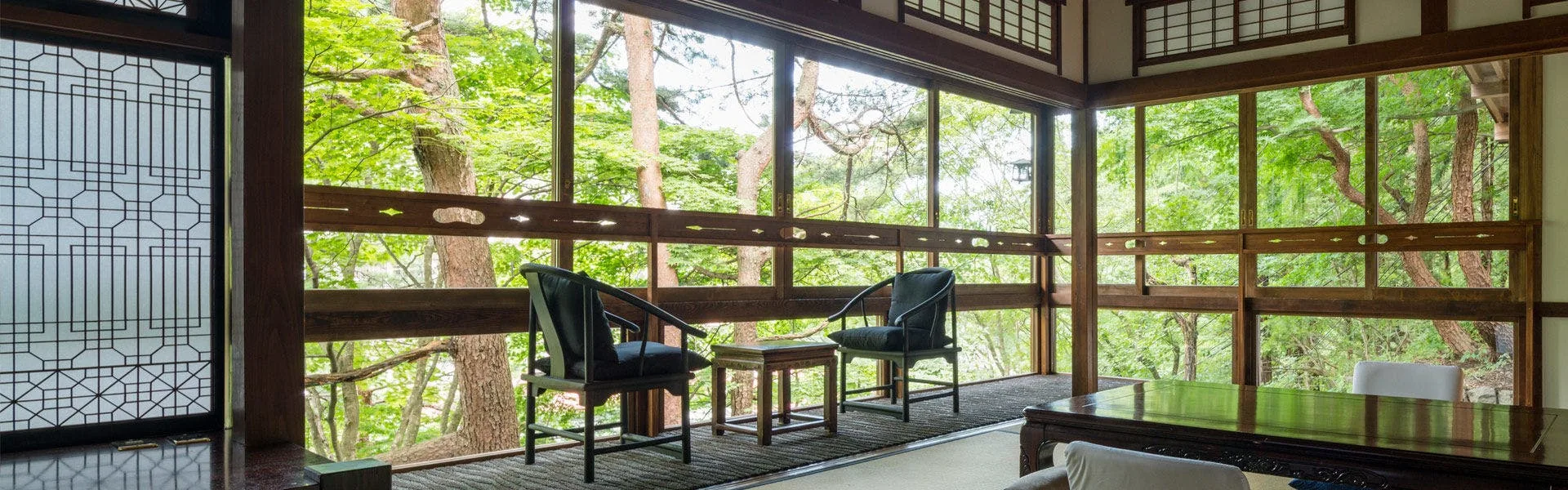 Kashoutei sitting room with floor-to-ceiling wood-framed windows into Shima Onsen forest