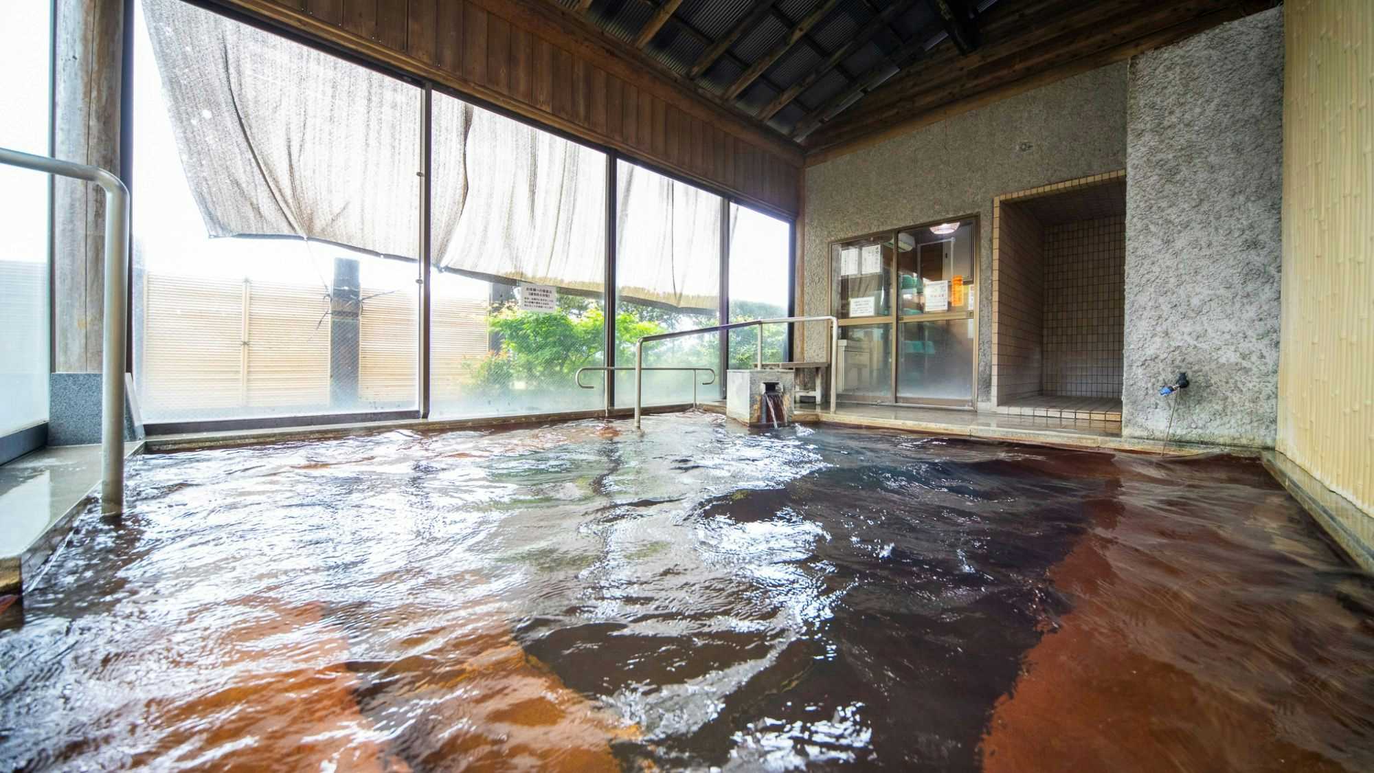 Ryokan Toyotomi with a spacious indoor bath overlooking mountains through wide windows.