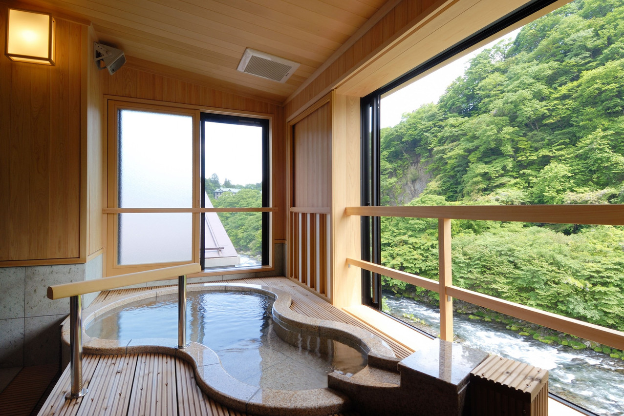 A deep soaking bath opens toward a wooded mountain view.