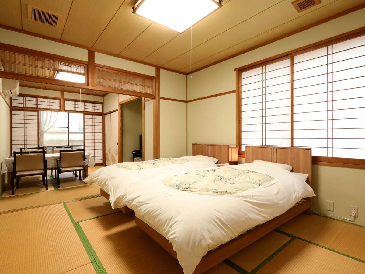 Mimata Onsen Kameya Ryokan two low beds in a tatami room with dining chairs beyond