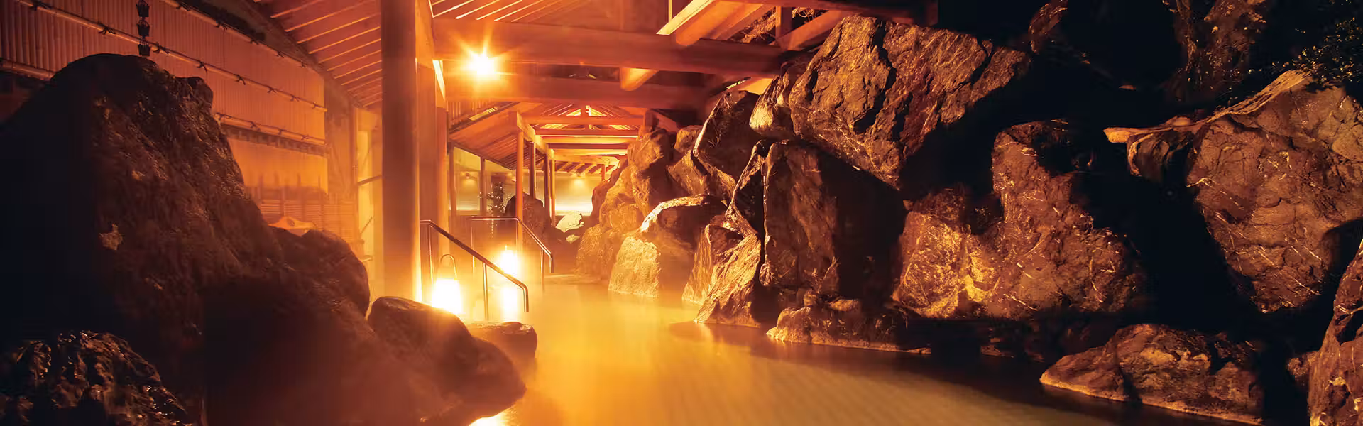 Shiratama no Yu Senkei with this scene, where a rock-lined open-air bath glows beneath timber rafters.