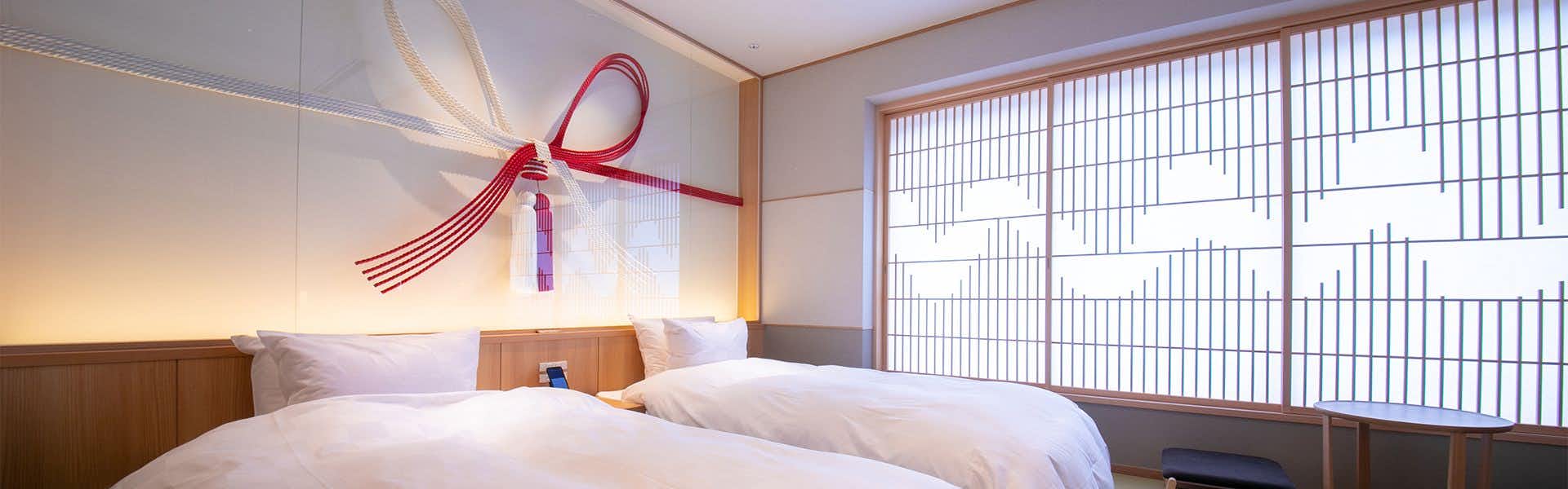 Sumihei Bettei Tokitoki White pillows against shoji screen window with gridded geometric light pattern, red textile detail on left wall