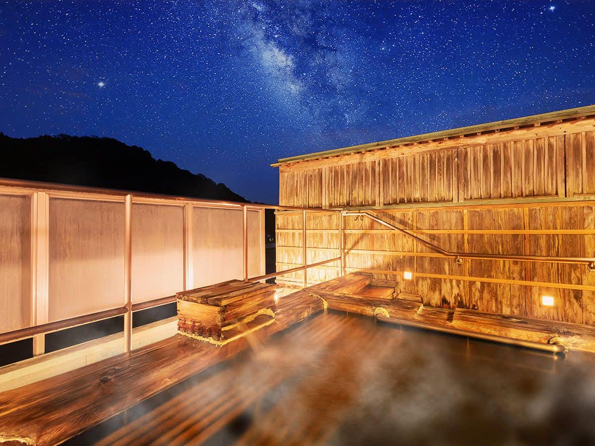 Yumoto Sakakibara-kan with a steaming open-air bath beneath a starry sky.