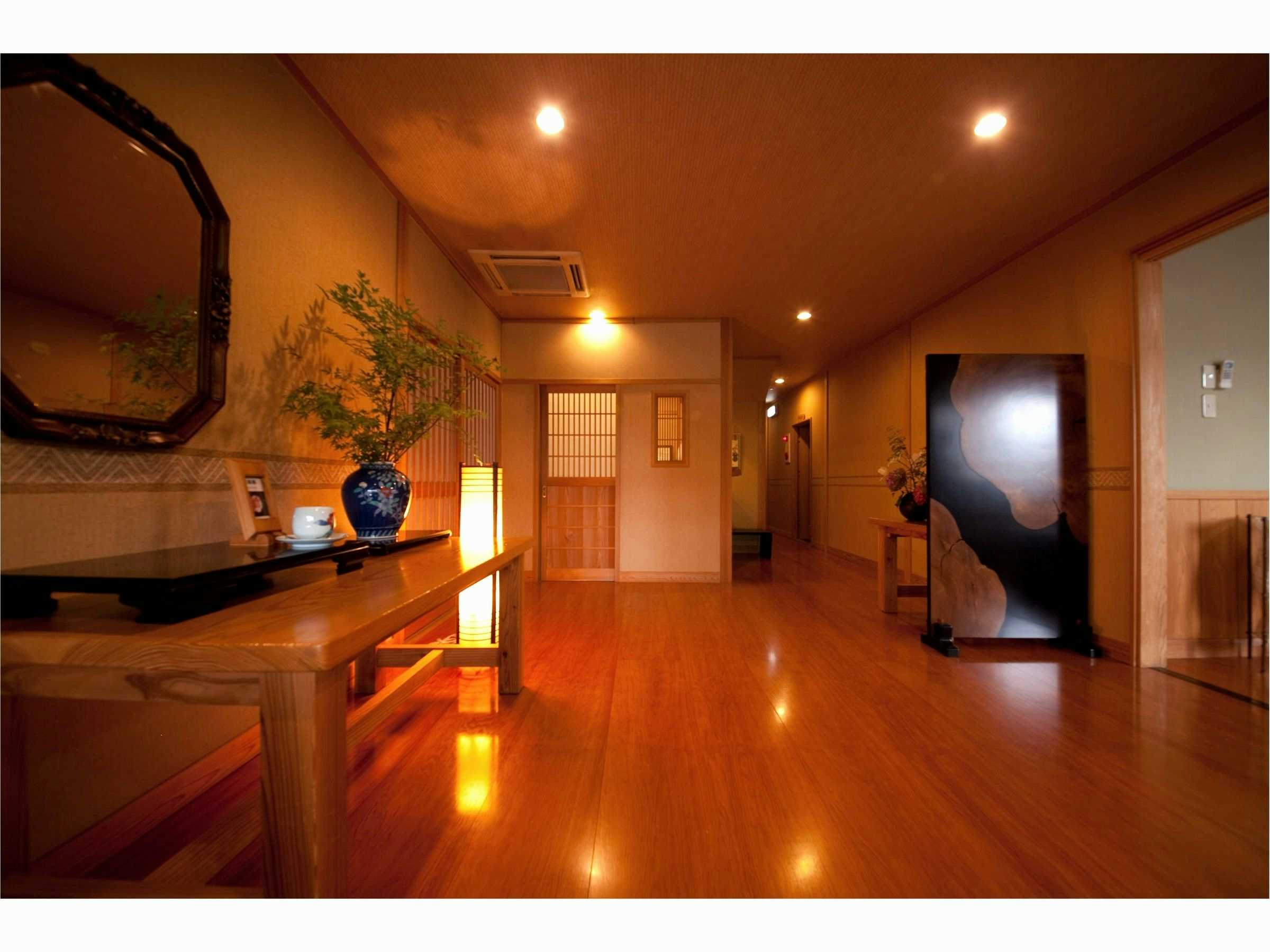 Oyado Yuraku with a polished timber corridor illuminated by warm floor lanterns.