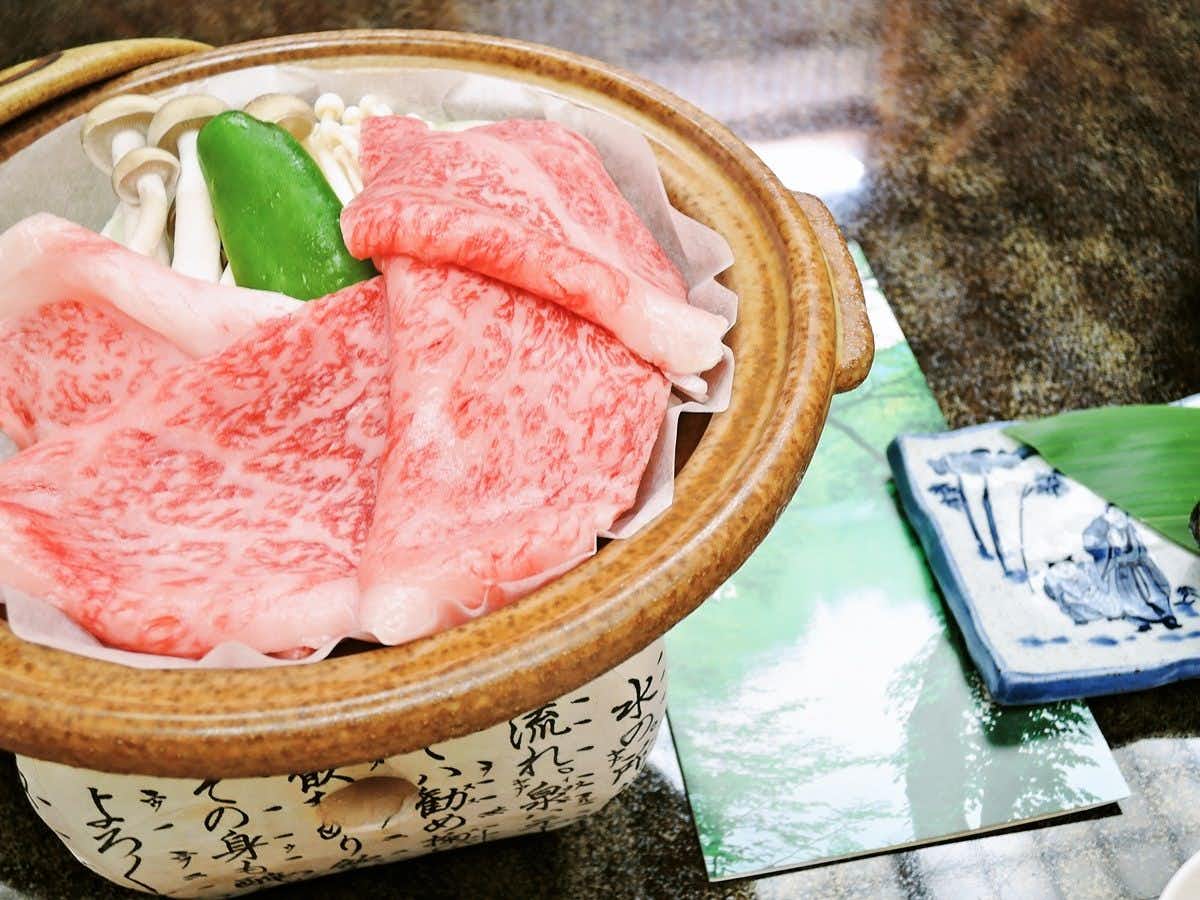 Iimikan Yoshine with marbled beef and vegetables arranged inside a ceramic pot.