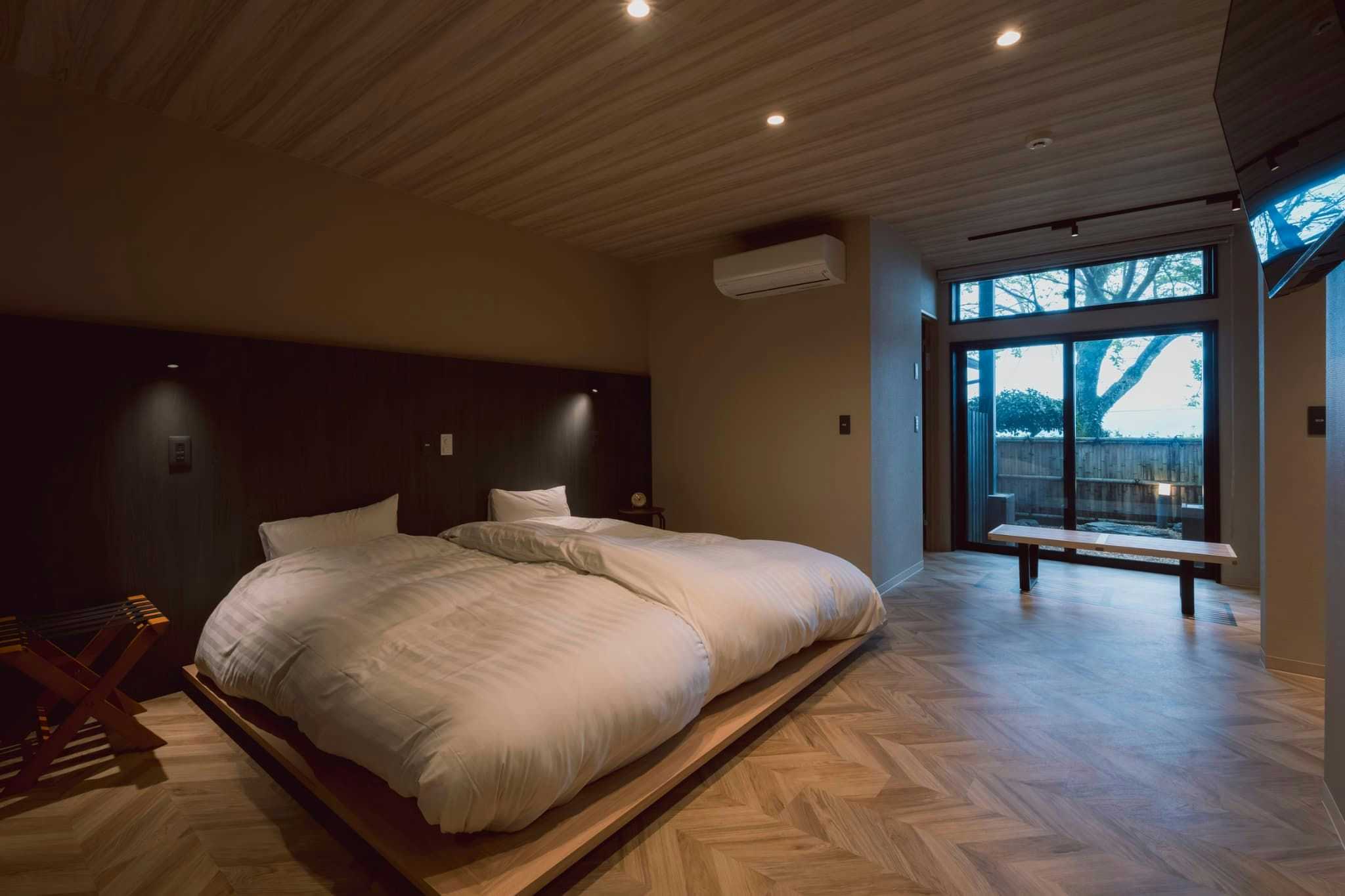 Hakusui Onsen Takenokura Sanso with a modern twin bedroom beside broad garden windows.