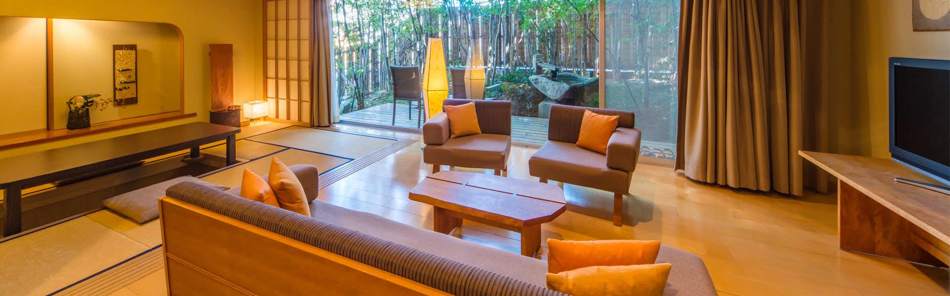 Kakujoro: A comfortable lounge with sofas facing leafy garden windows.