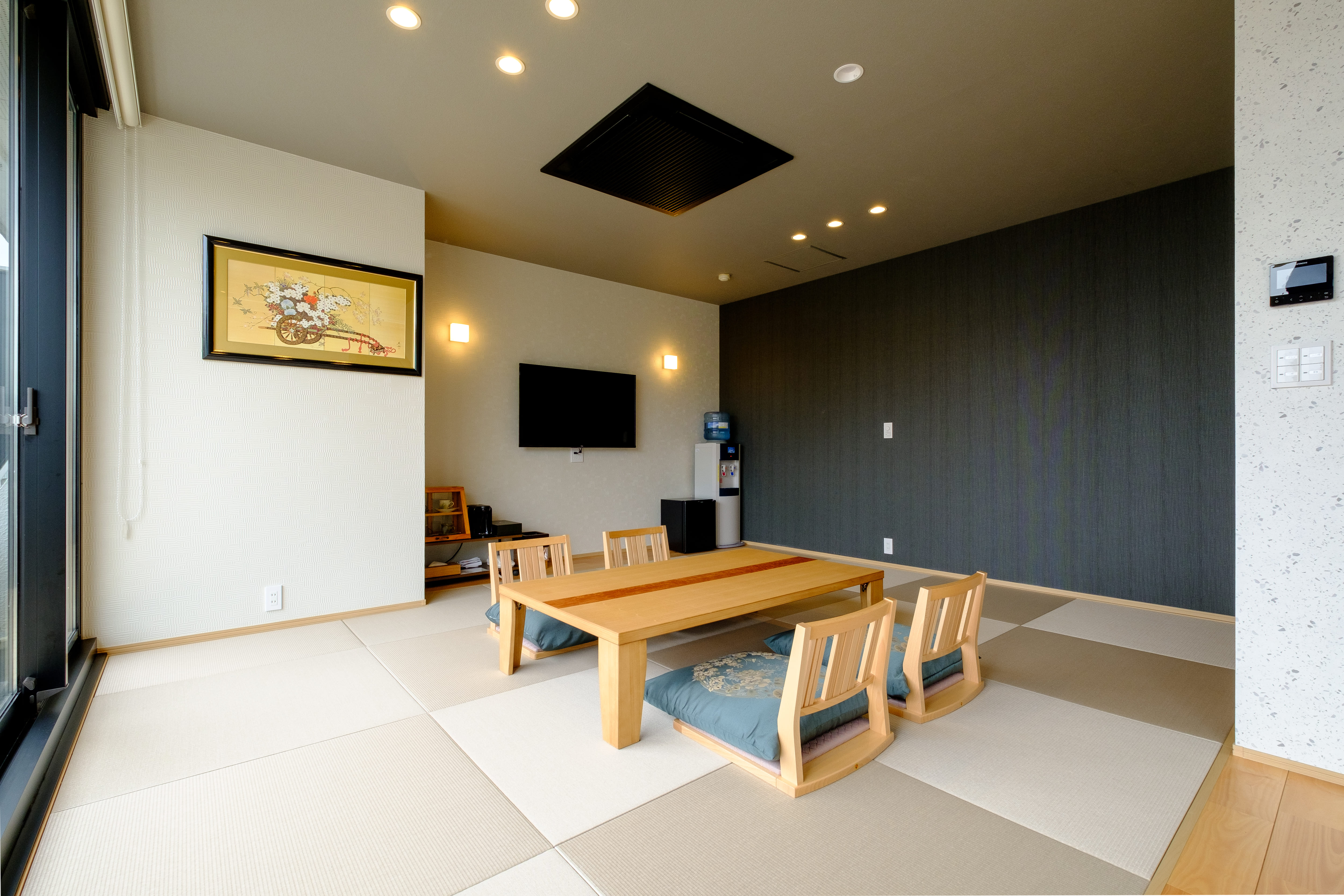 A tatami sitting room with a low dining table and wall-mounted television.