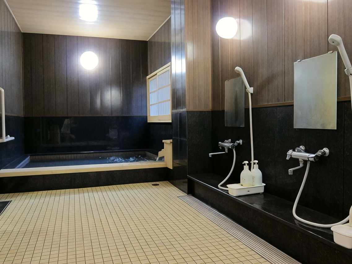A bathing room with dark walls, shower stations, and tatami-style flooring.